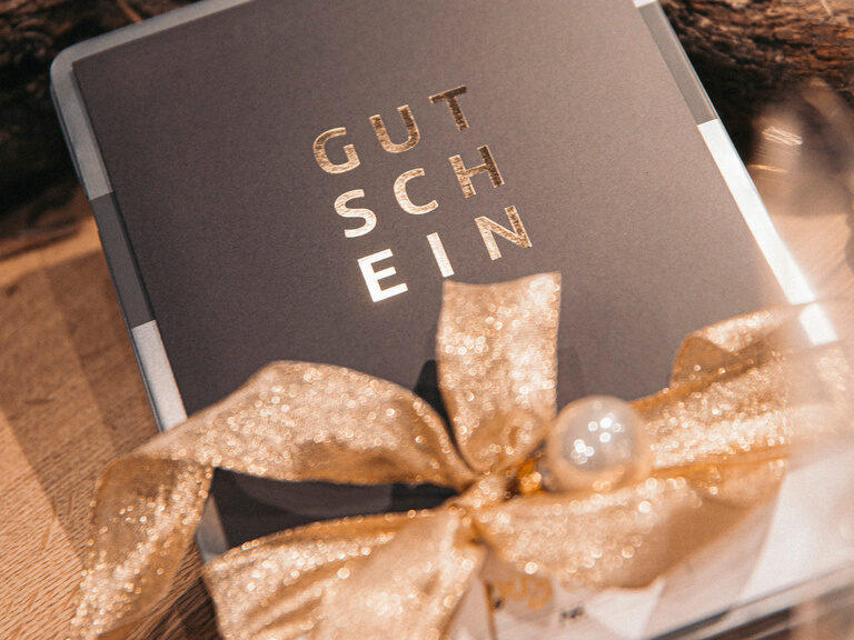Ein Gutschein dekoriert mit einer Schleife auf einem Tisch
